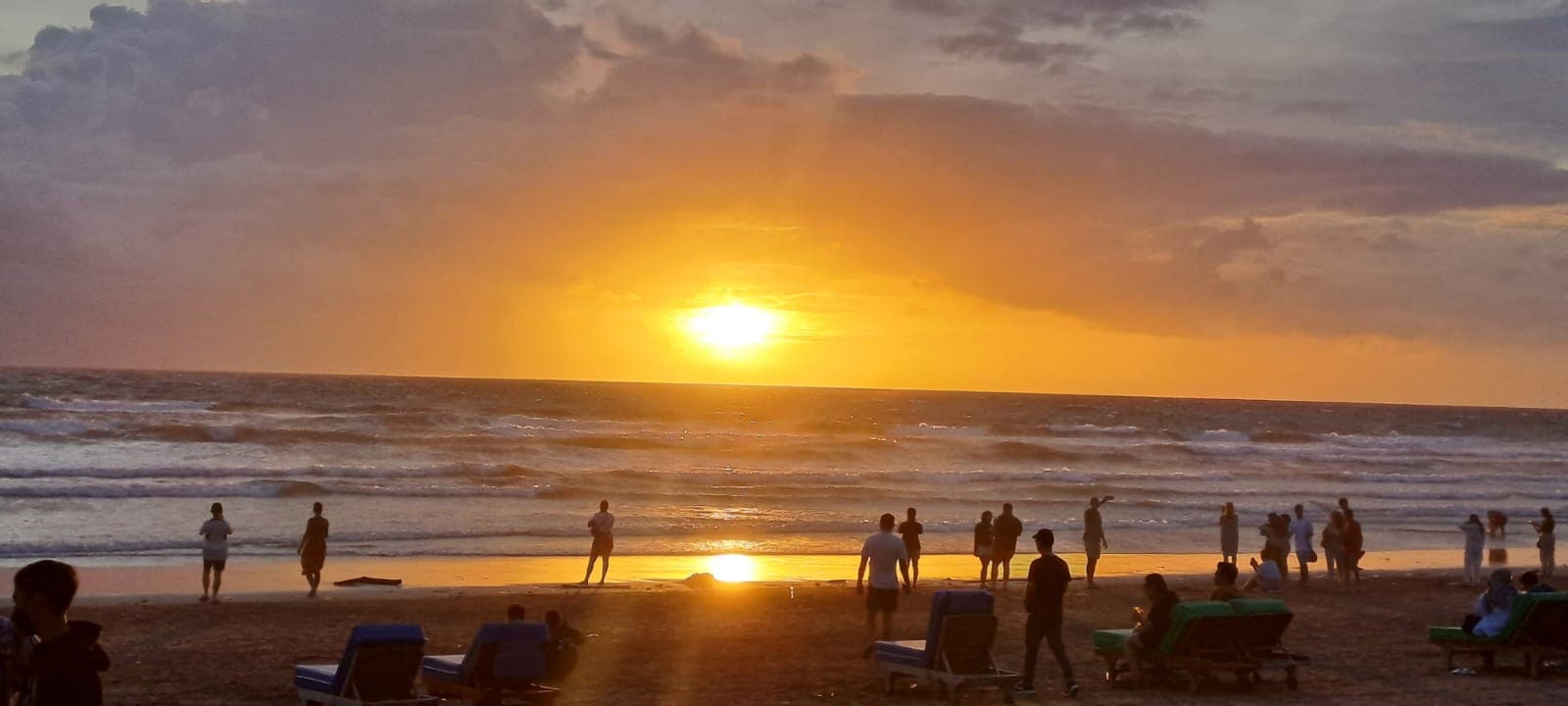 Zonsondergang op het strand van Canggu met mensen langs de vloedlijn